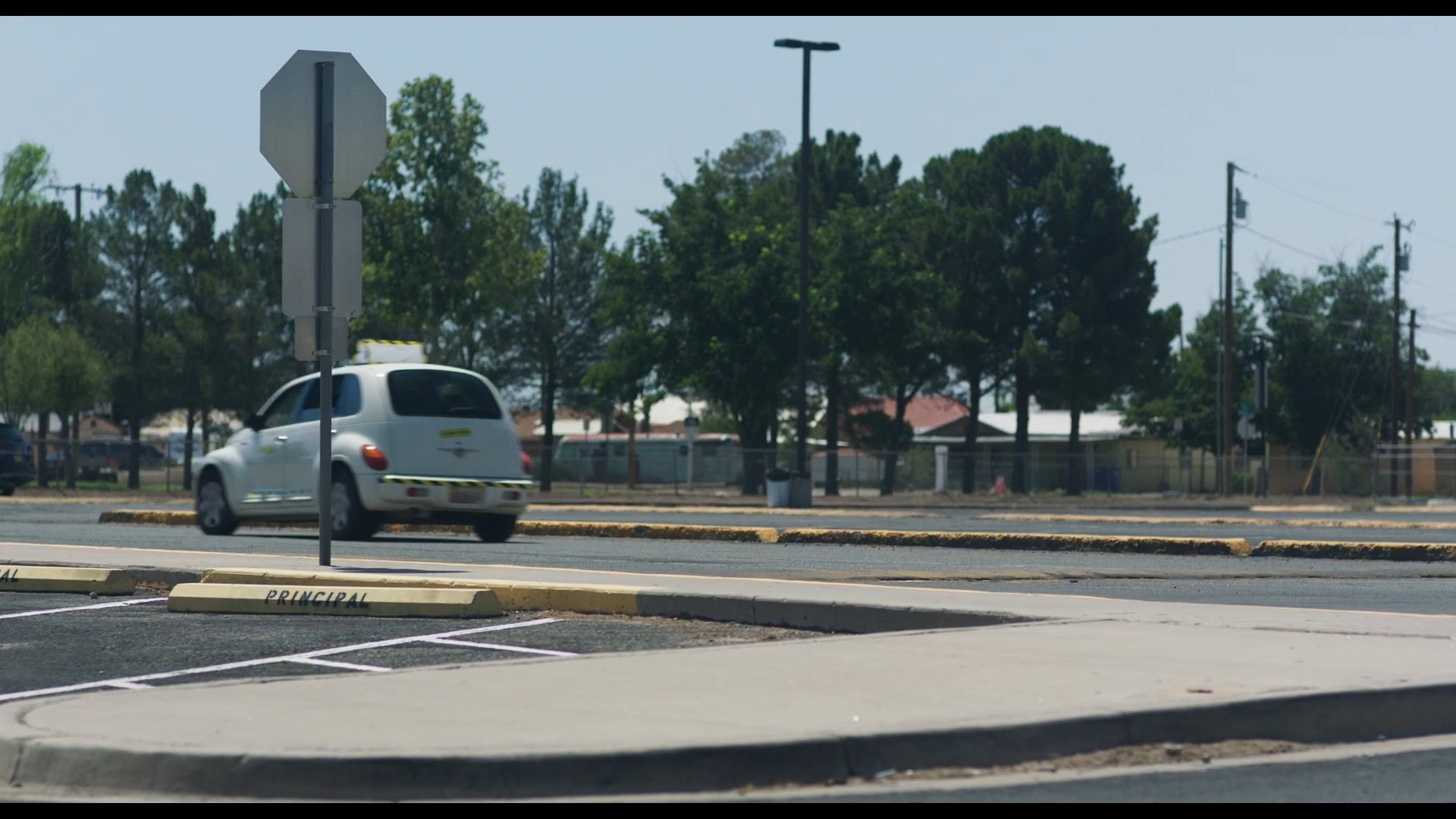 A student walks through a school parking lot while a taxi drives by, subsequently capturing an interior scene of a driver and passenger engaged in conversation.