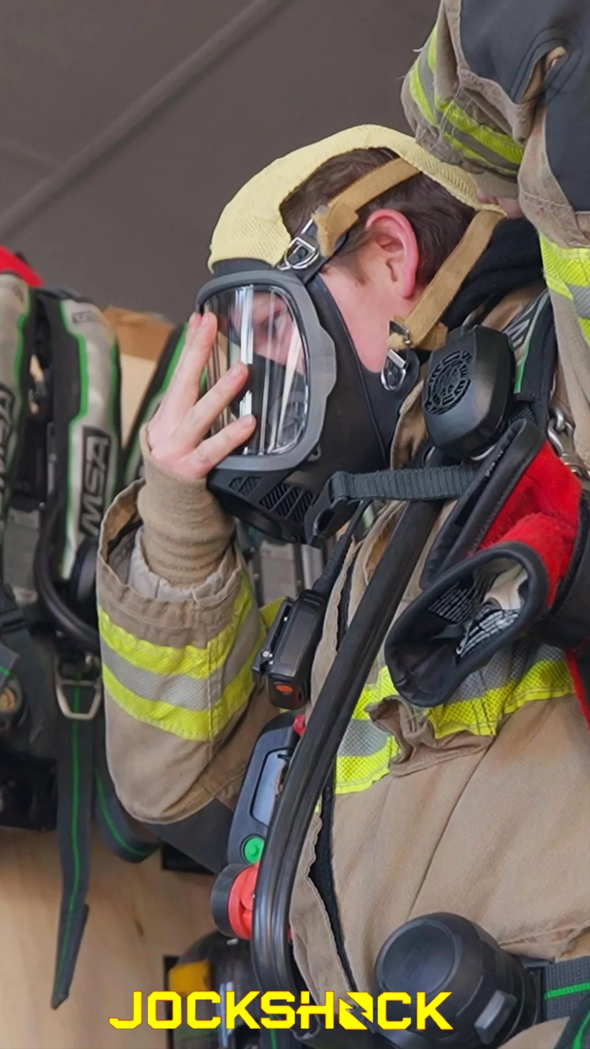 Firefighter donning SCBA and turnout gear in the apparatus bay