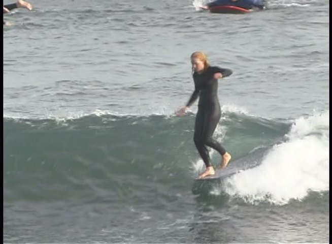 A surfer rides waves in a wetsuit, followed by a professional interview with Maranda Pitts Guzman regarding the session.