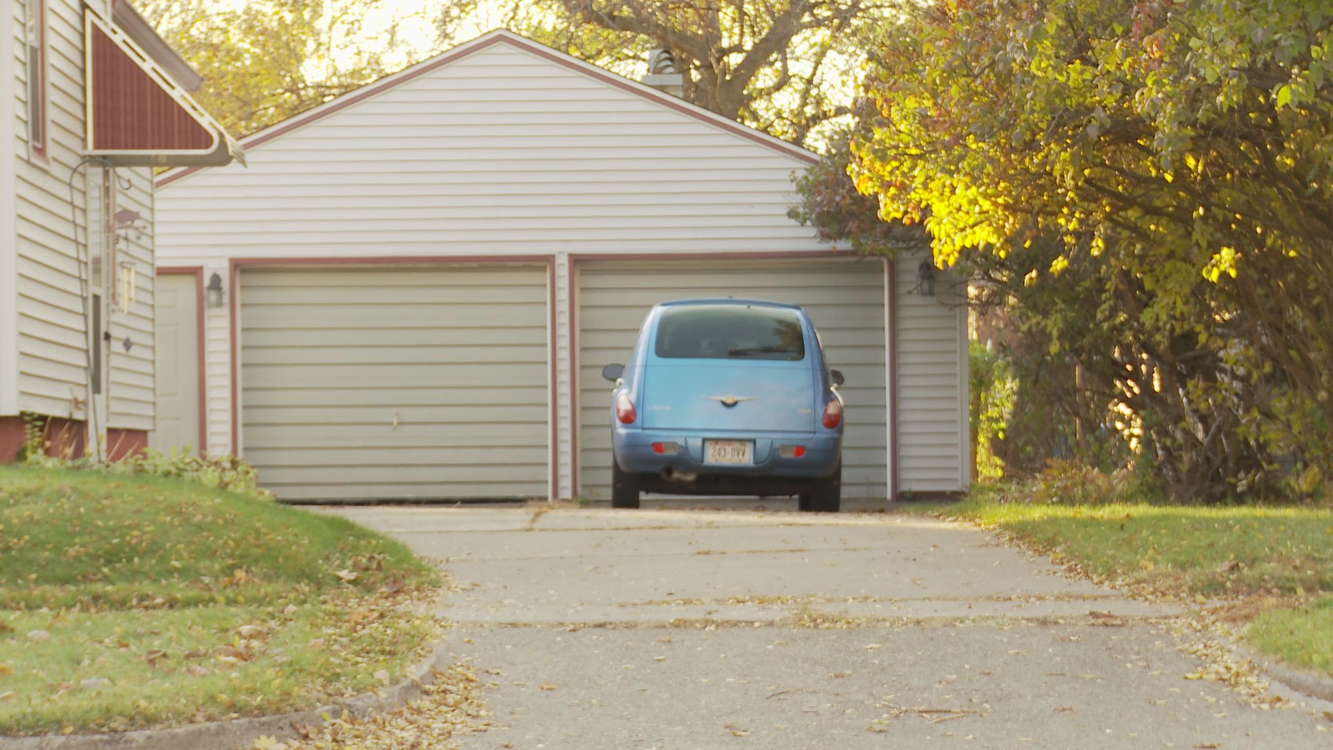 A woman engages in a telephone conversation while a man adjusts picture frames on a wall in their home, interspersed with exterior views of their garage.