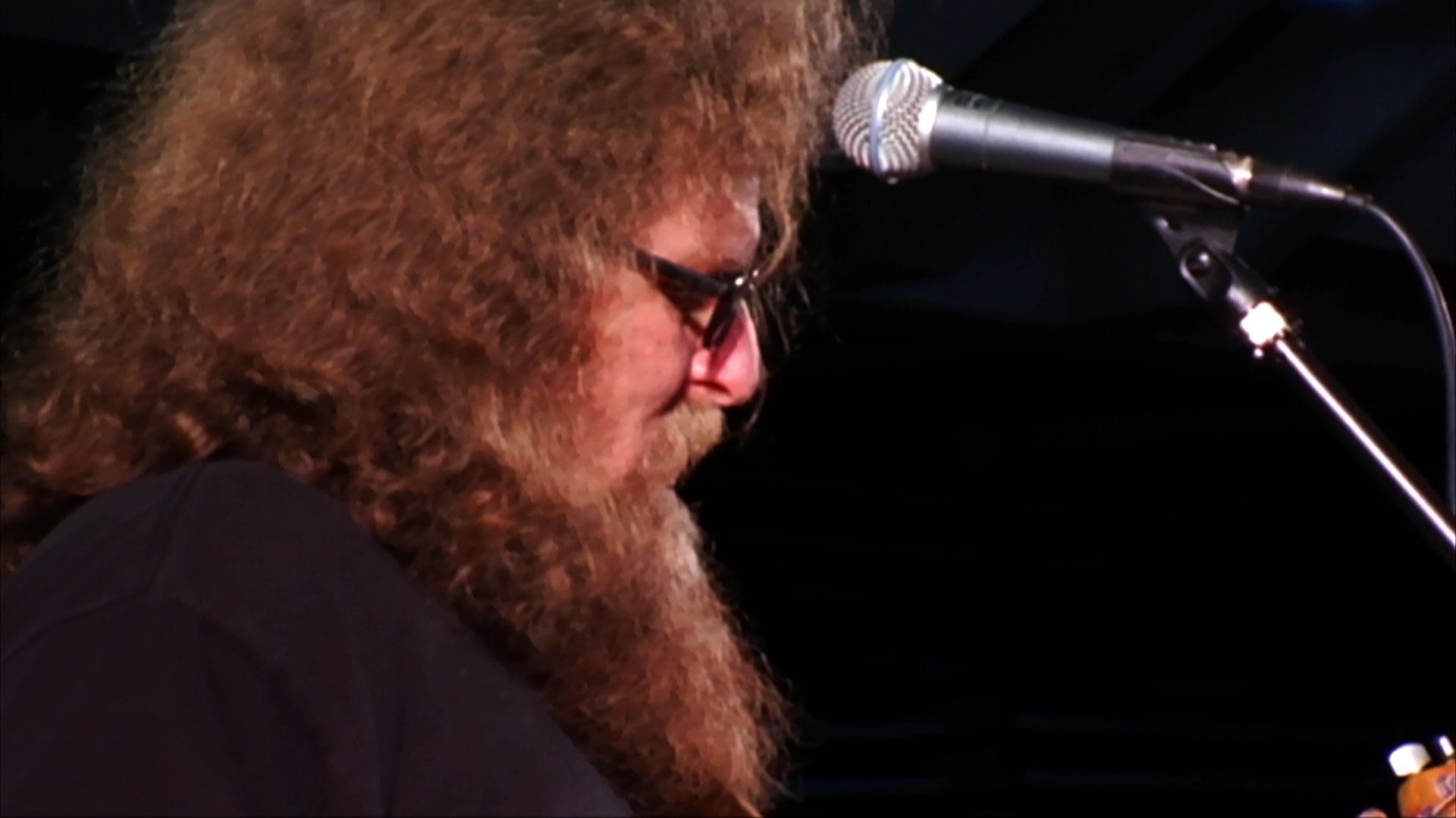 Two guitarists perform on a stage during a live concert event, focusing on their musical instrumentation. The scene captures the intensity and concentration of the musicians as they play before an audience.