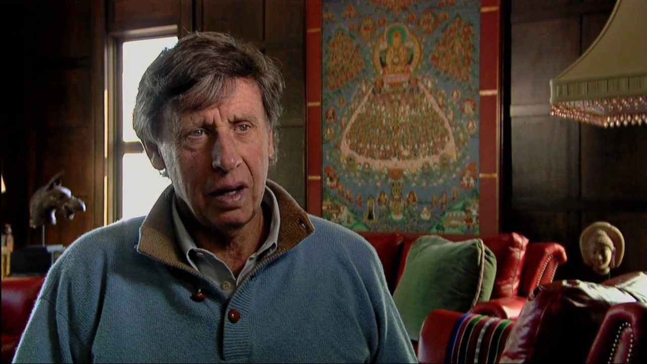 A man engages with local residents in a high-altitude Himalayan setting before reflecting on his experiences inside a traditional room. The group later visits a sacred monastery site to continue their journey.