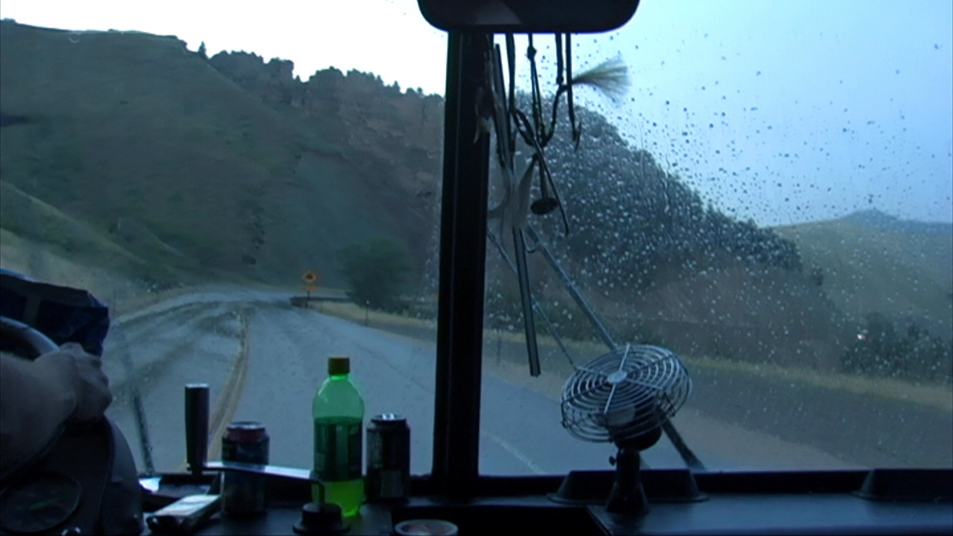 A group of musicians prepares for a live performance at an outdoor venue before continuing their journey on a tour bus through a scenic mountain road.