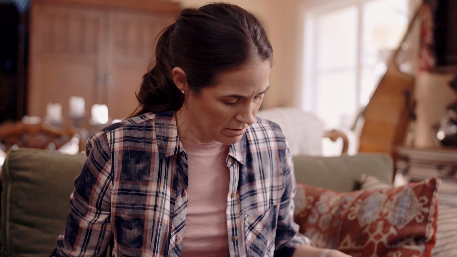 A man and woman engage in a serious, quiet conversation while sitting together in a residential living room setting. The exchange focuses on emotional processing and interpersonal communication within a domestic environment.