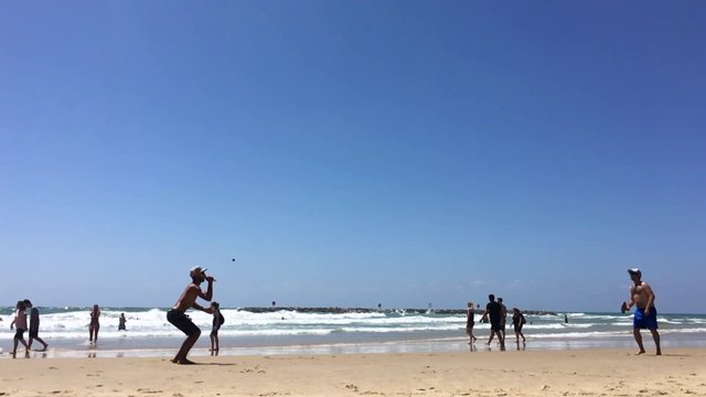 Dos amigos jugando al pádel en la playa