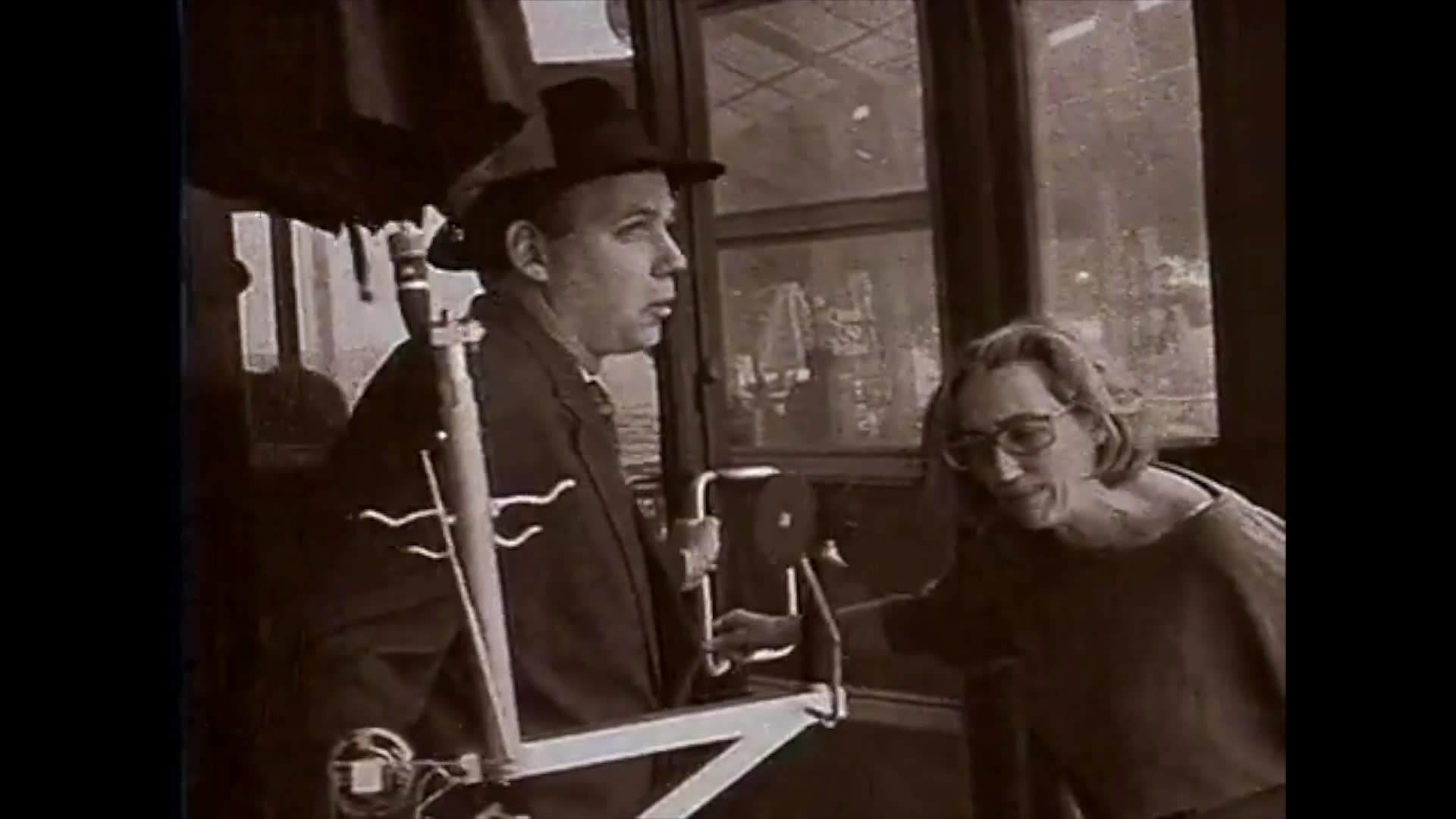 A camera operator on a monowheel captures an interaction between a woman and a man in a formal setting. The sequence illustrates the collaborative process between performers and technical crew during a film shoot.