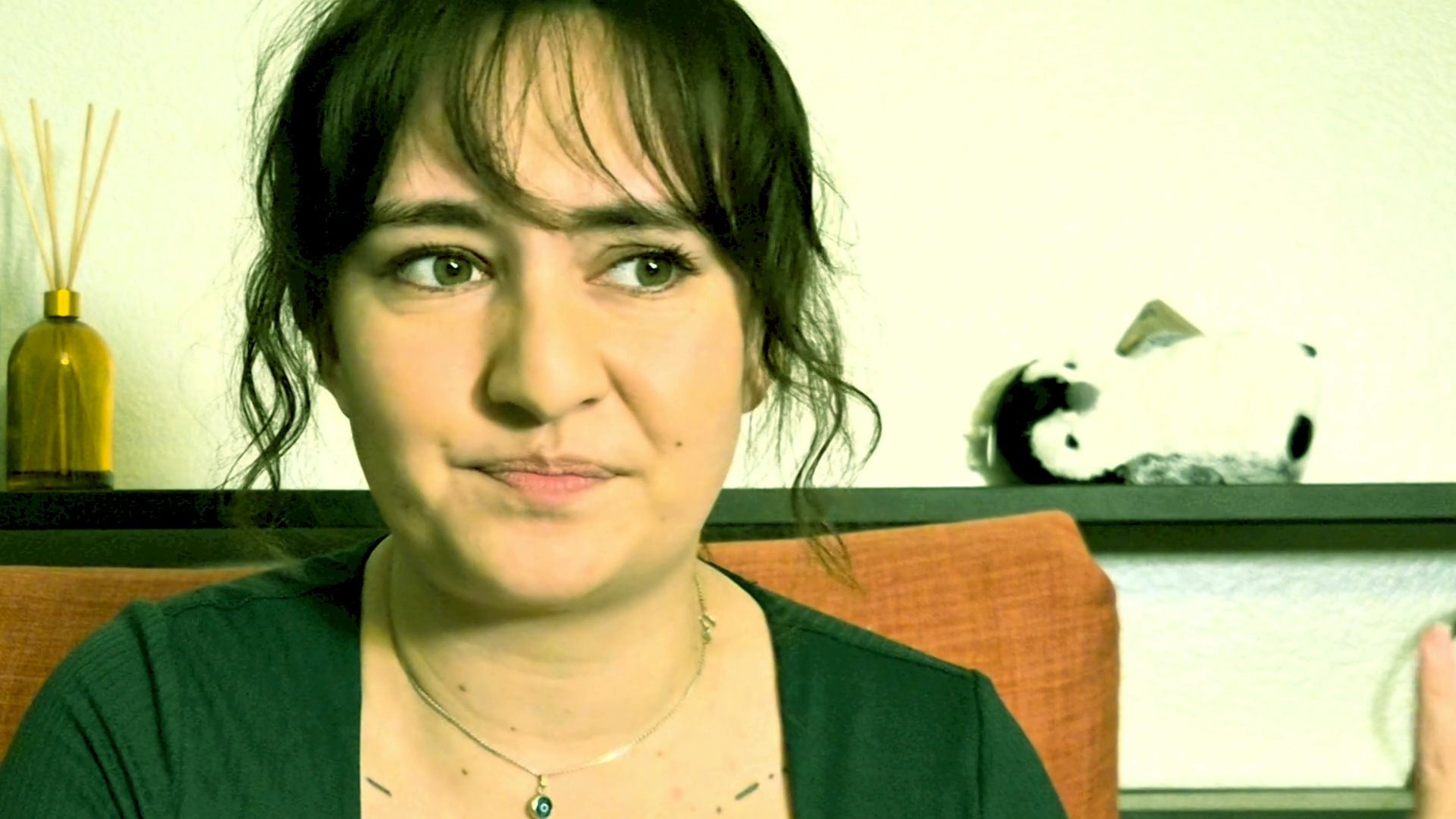 A woman speaks directly to the camera in a conversational tone, using hand gestures to emphasize her points.