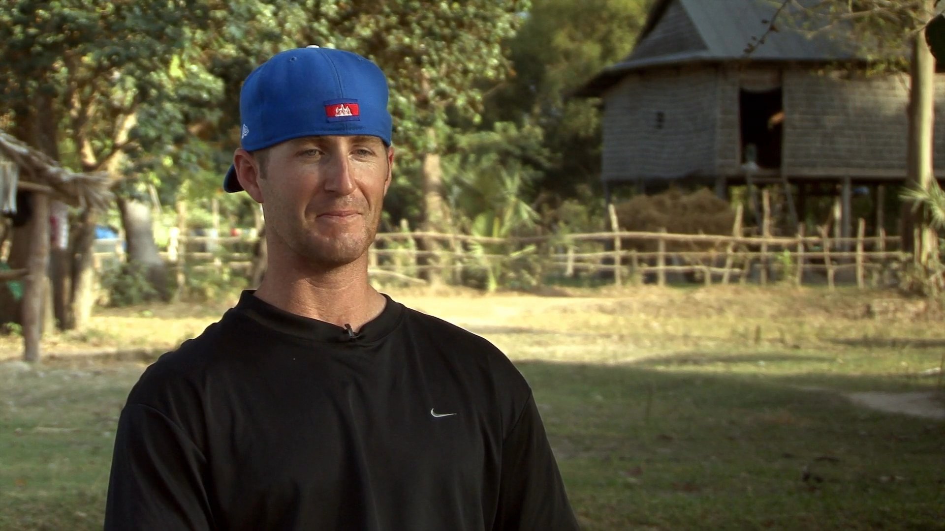 A coach works with a group of young baseball players in an outdoor training setting, followed by an interview segment. The interaction highlights professional instruction and the development of youth athletes.