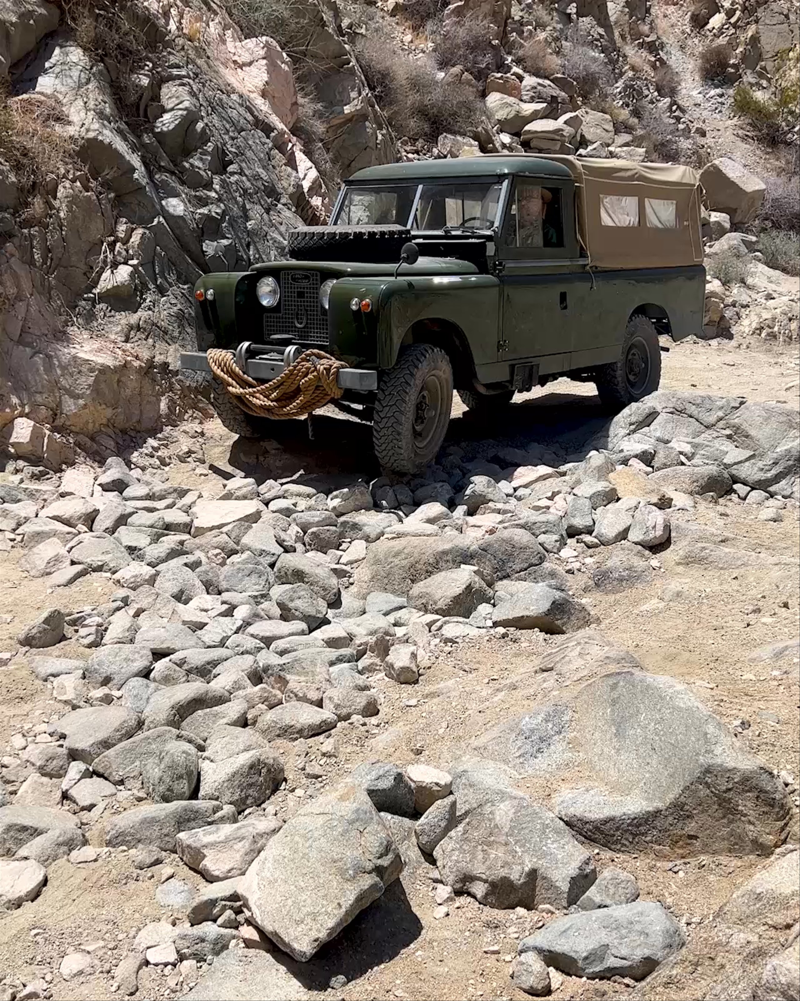 Vintage Land Rover off-roading over boulders in Joshua Tree