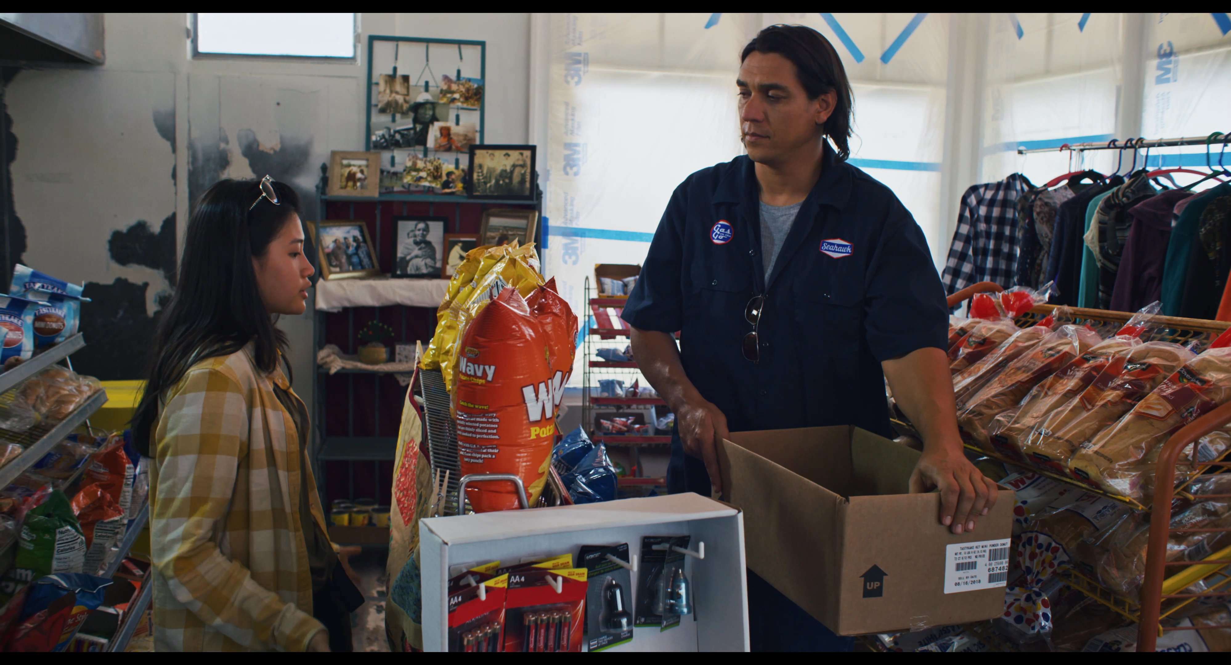 A store employee engages in a professional conversation with a customer while organizing inventory in a retail space.