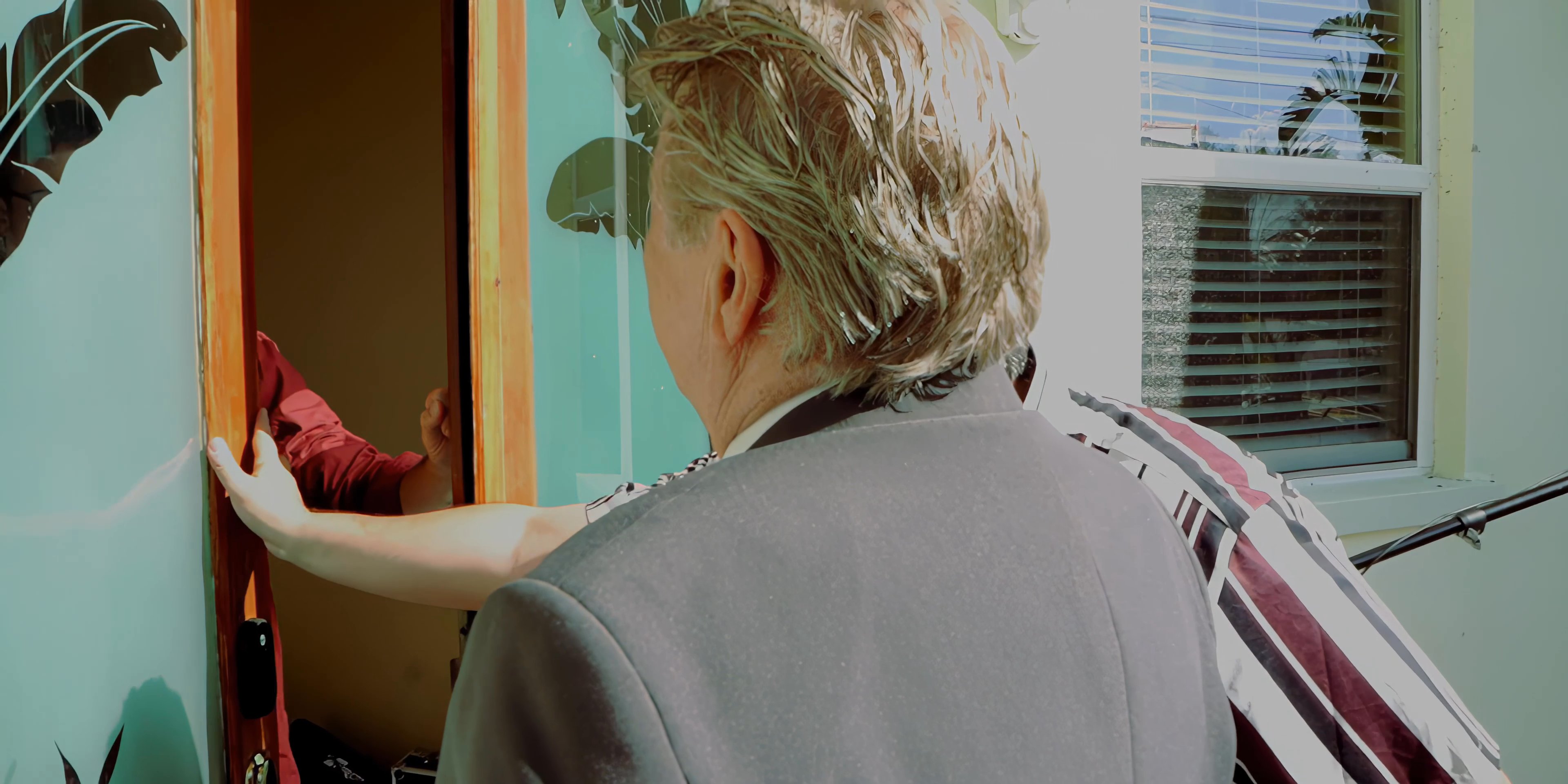 Two men arrive at a residence and engage in an initial conversation with the occupant standing at the entrance. The interaction proceeds as the guests are welcomed into the home.