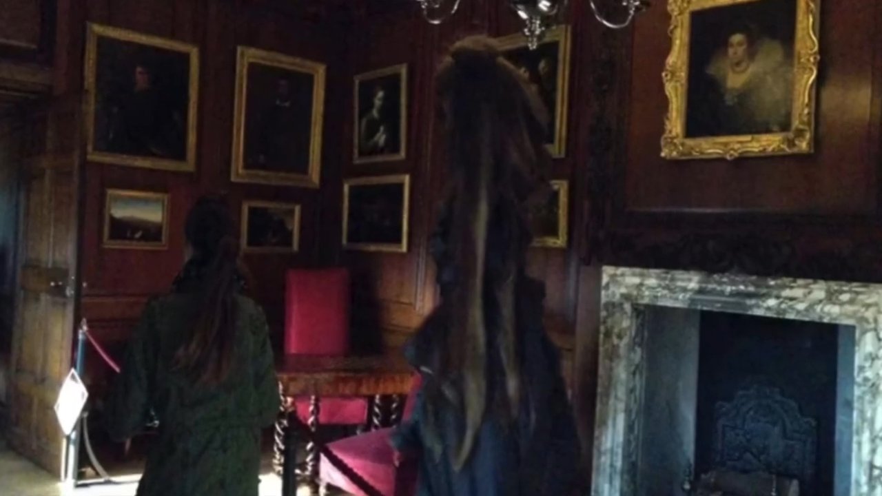 An observer navigates the interior of a historic mansion filled with portraits, transitioning between atmospheric shots of the building's exterior and its dark, ornate rooms.