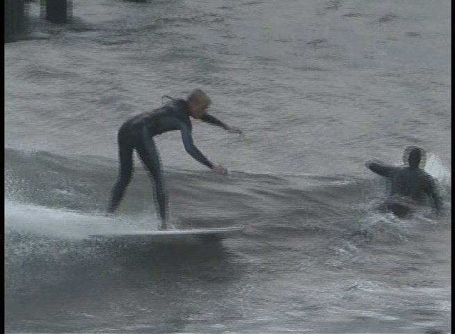 A surfer in a wetsuit skillfully navigates powerful ocean waves, performing dynamic turns and aerial maneuvers. The sequence highlights technical precision amidst challenging surf conditions.
