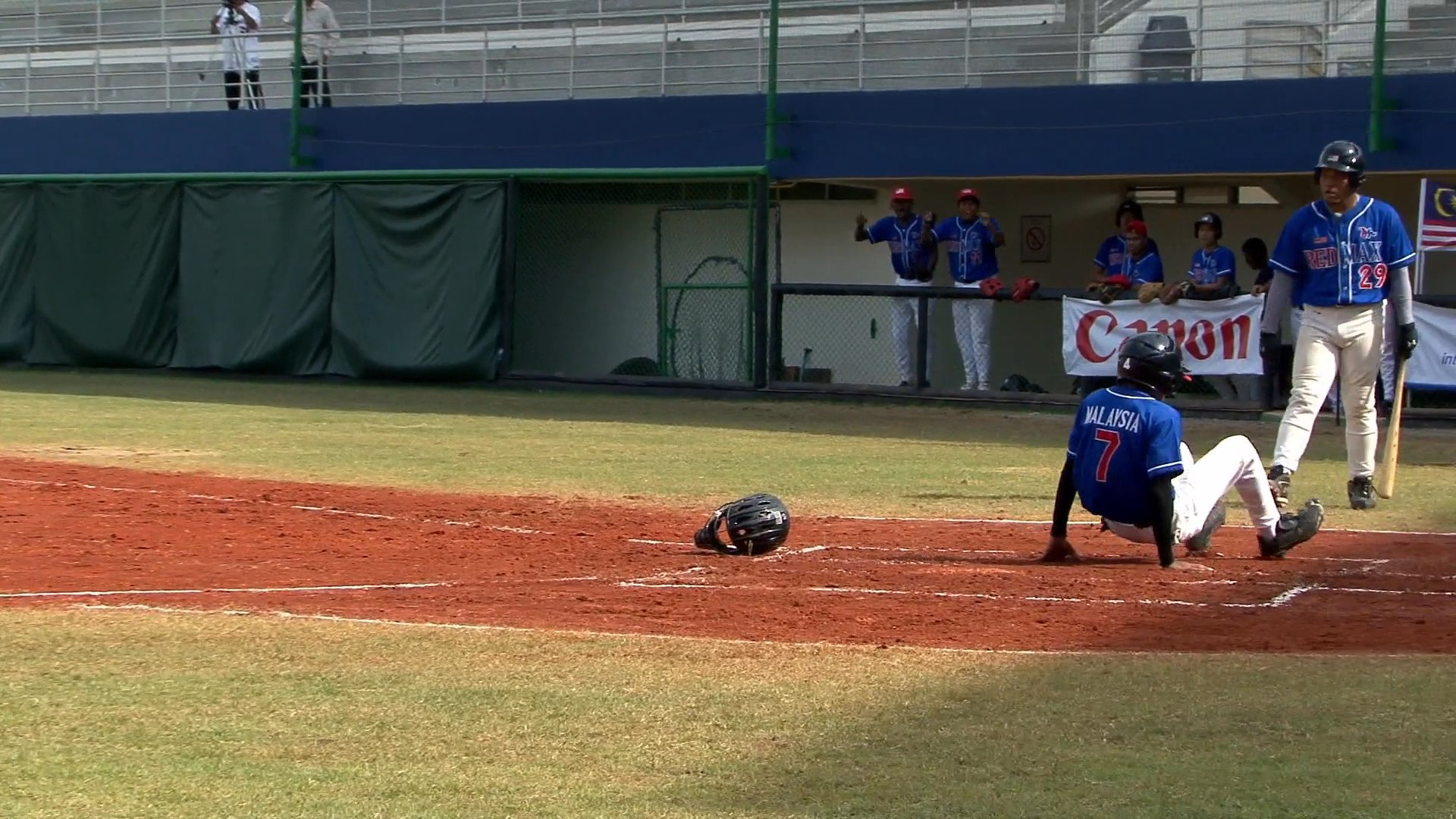 Players compete in a baseball game between Cambodia and Malaysia, featuring active batting, pitching, and base running sequences as displayed on the scoreboard.