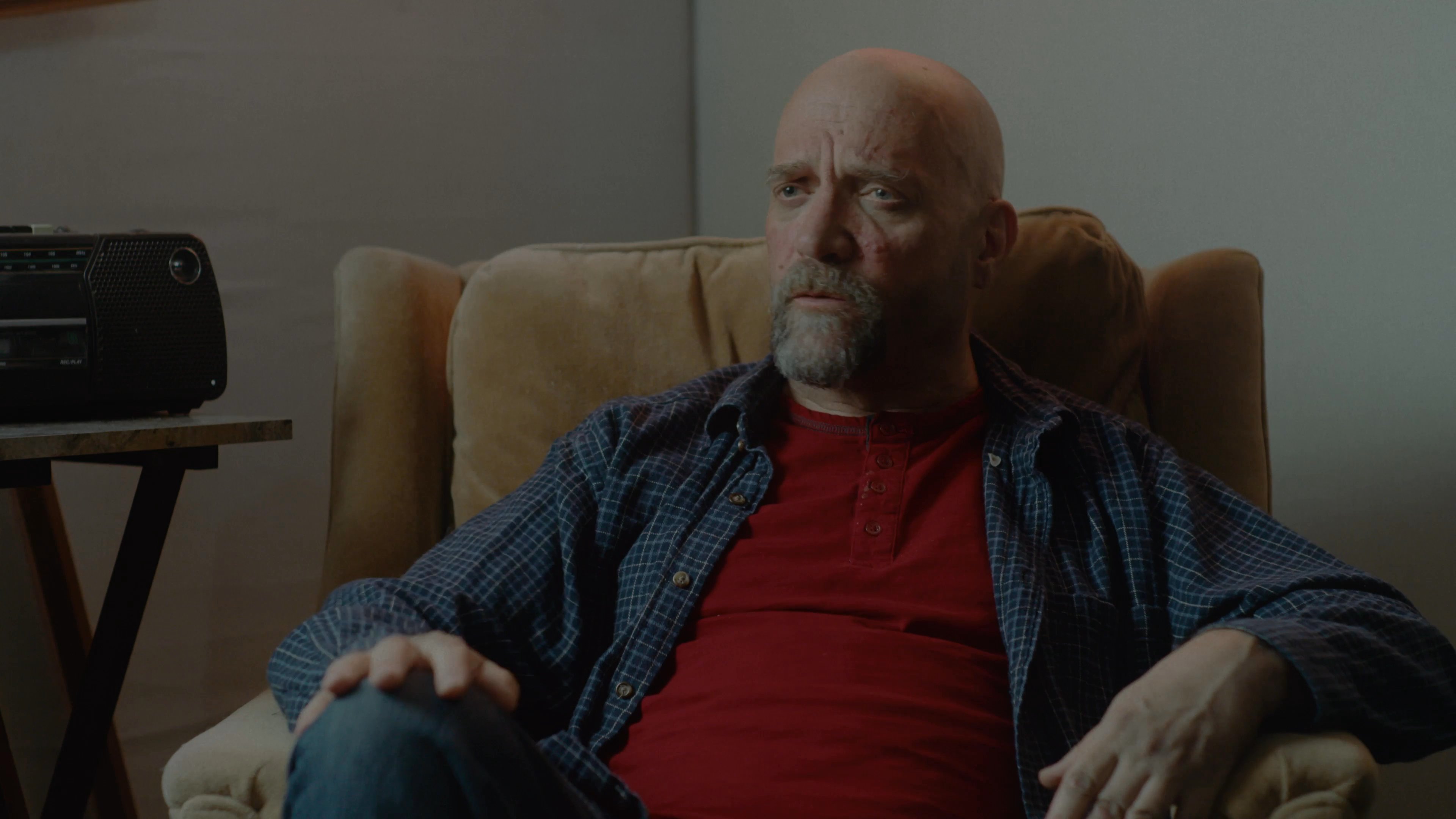 Two men sit in a living room and engage in an informal, seated conversation.