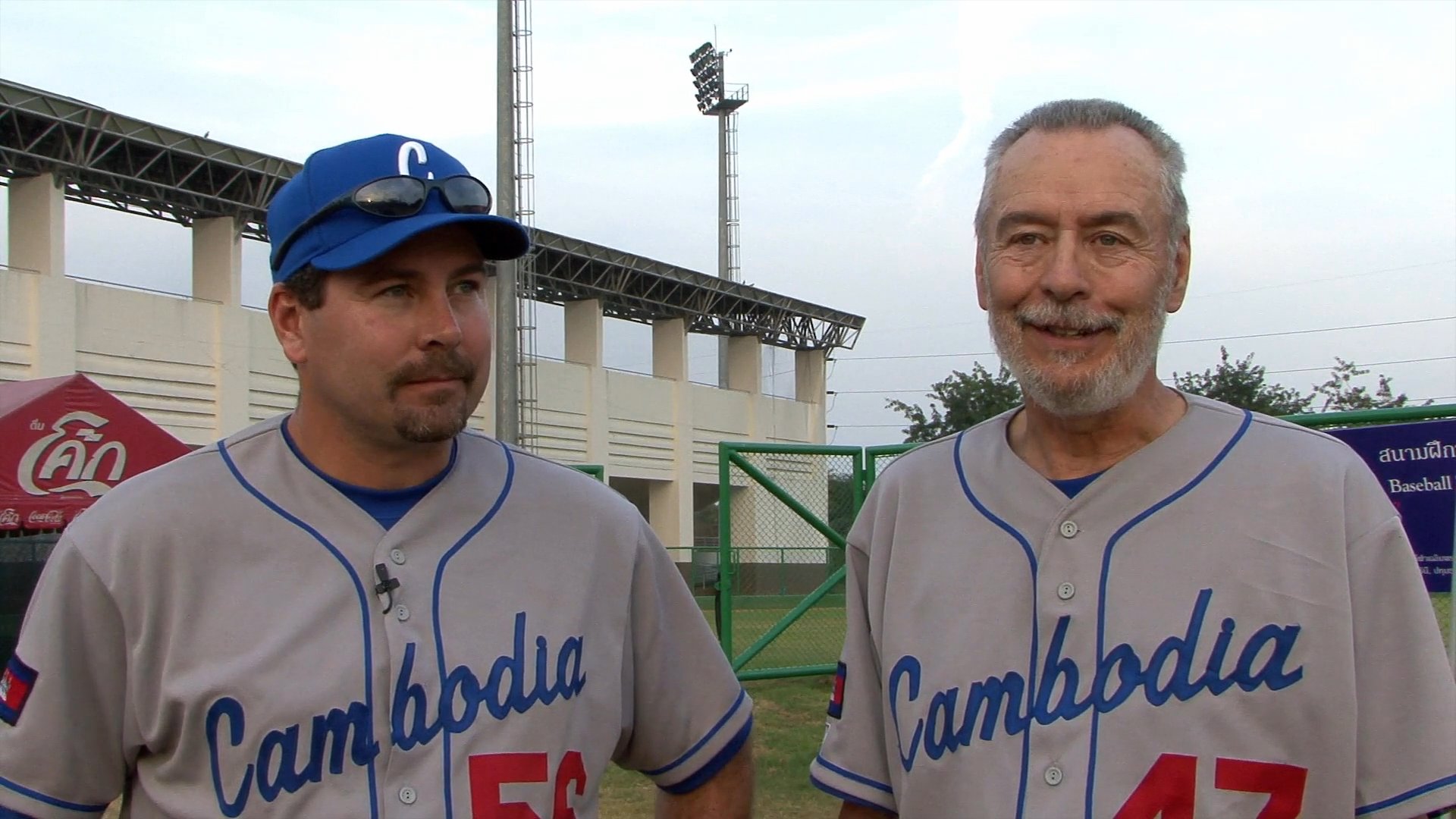 Players and coaches for the Cambodia national baseball team discuss their experiences and dedication to the sport on a baseball field. The dialogue highlights the growth of baseball within the country and the camaraderie among team members.