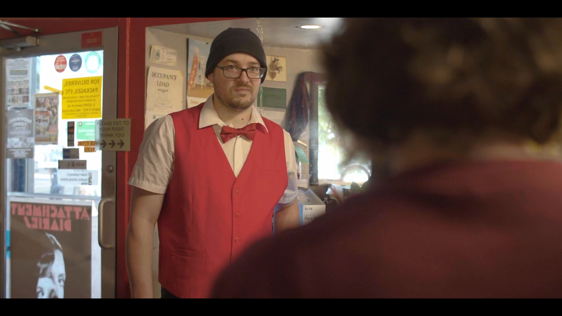 A concession stand worker assists a distressed patron by providing medical attention after they arrive at the cinema entrance.