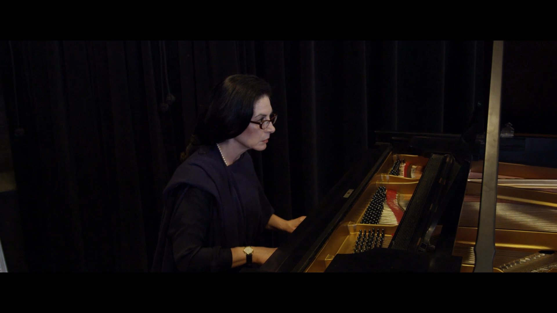 A group of dancers practices choreography in a professional studio accompanied by live piano music. The rehearsal emphasizes precise movements and artistic technique under expert guidance.
