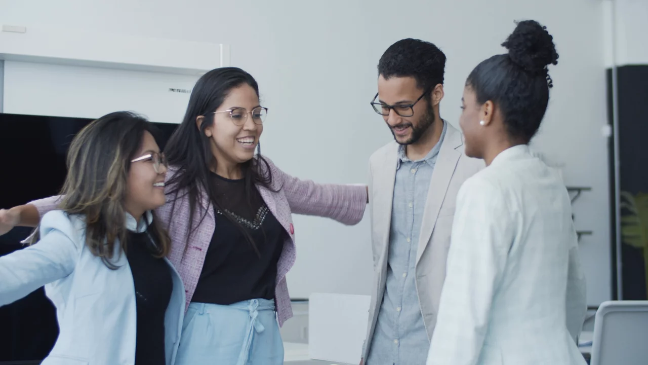 Colleagues hugging and celebrating together in a bright office
