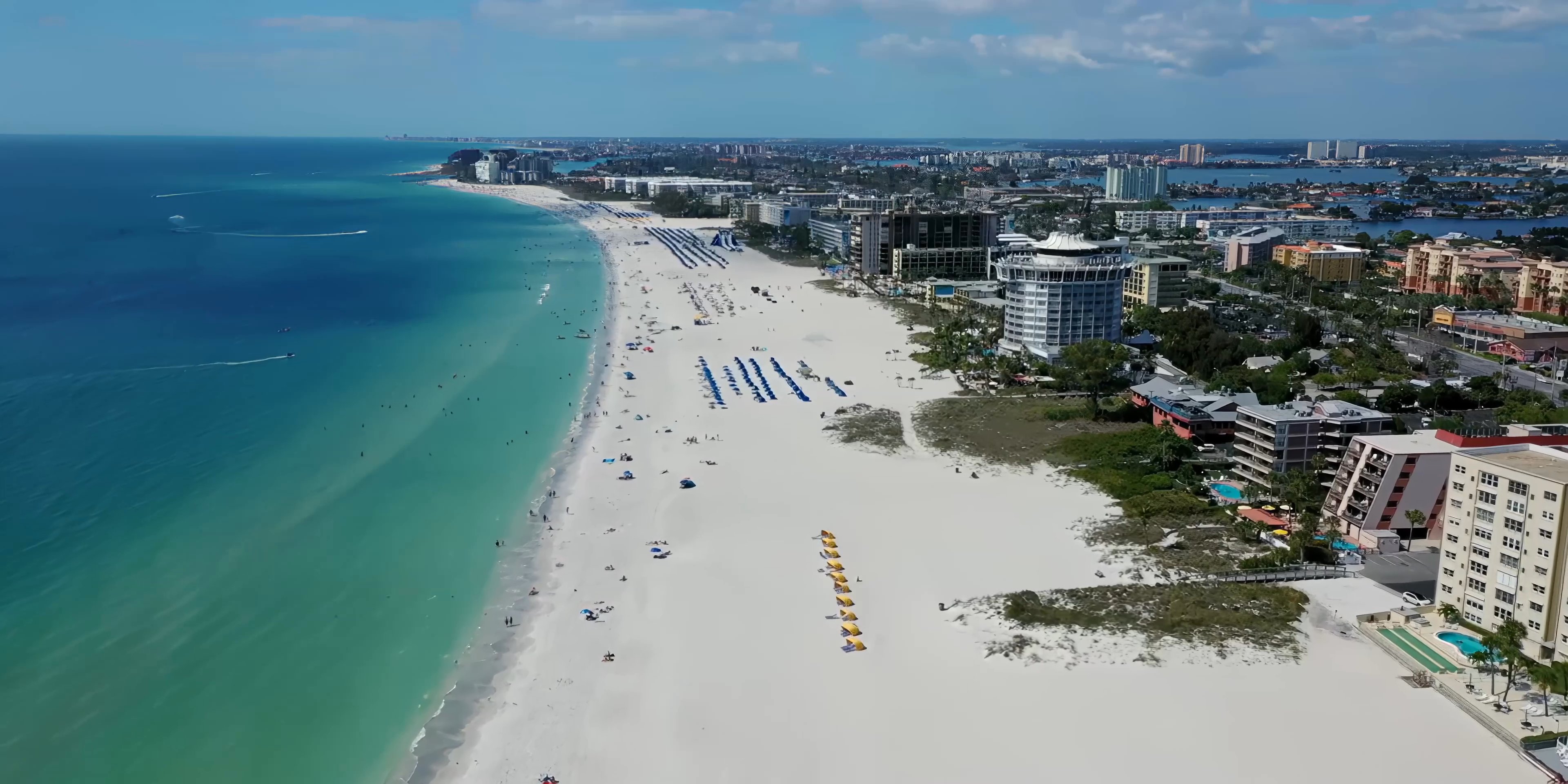 A transition sequence shifts from an indoor bedroom setting to vibrant aerial views of city skyscrapers at sunset, coastal beaches, and lush parkland.