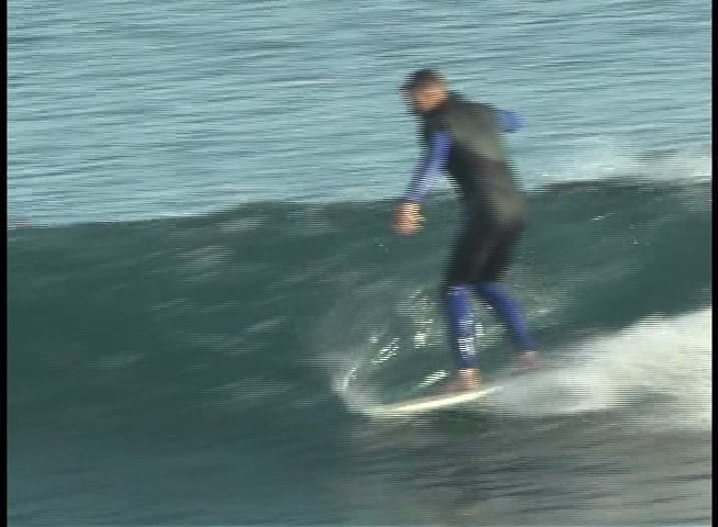 A surfer wearing a wetsuit skillfully rides multiple waves in the open ocean. The sequence captures the individual maintaining balance and navigating the surf.