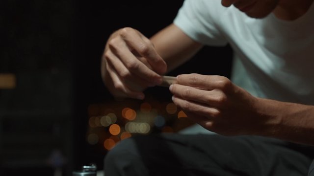 A man carefully prepares joint to smoke