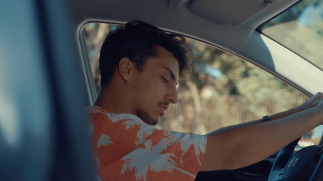 Teenage boy sitting in his car bopping his head to music