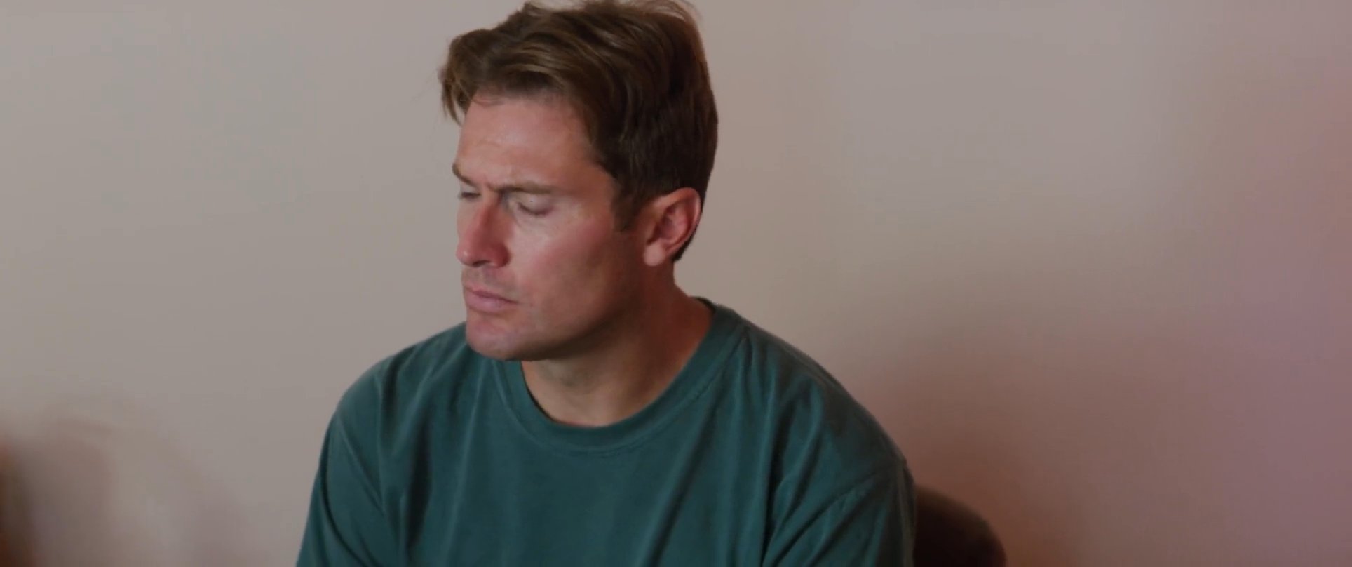 Two men engage in a serious conversation while sitting in a residential setting. They alternate focus as they speak to one another in an indoor space.