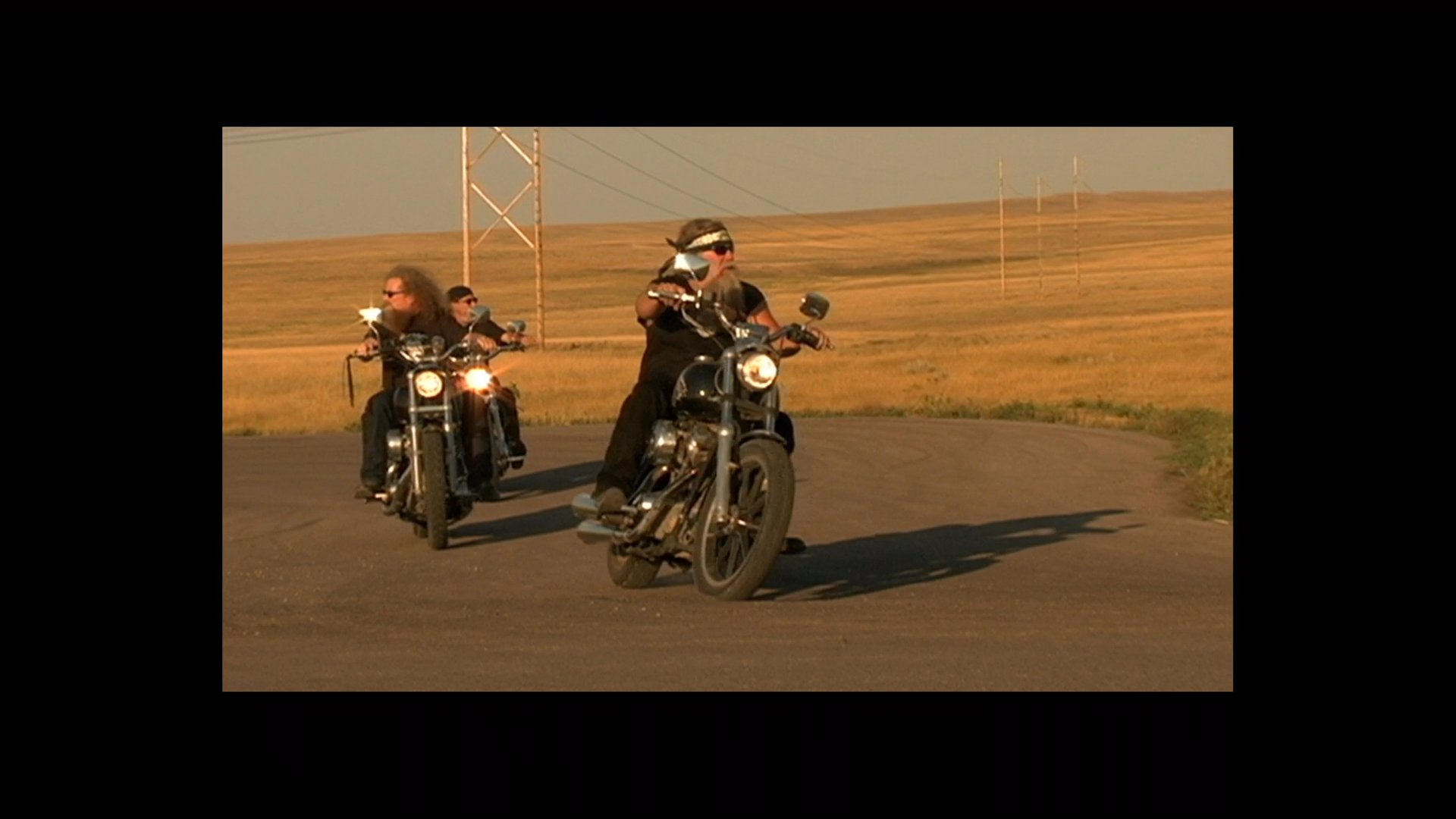 Motorcyclists ride cruisers across an open, golden prairie landscape during the closing film credits. The sequence concludes with a memorial tribute to specific individuals.