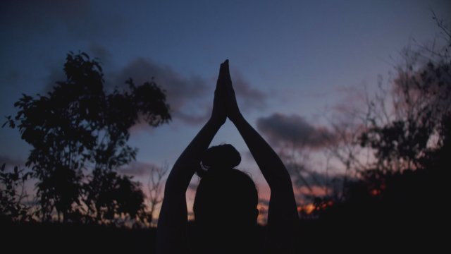 Una mujer practicando yoga al atardecer