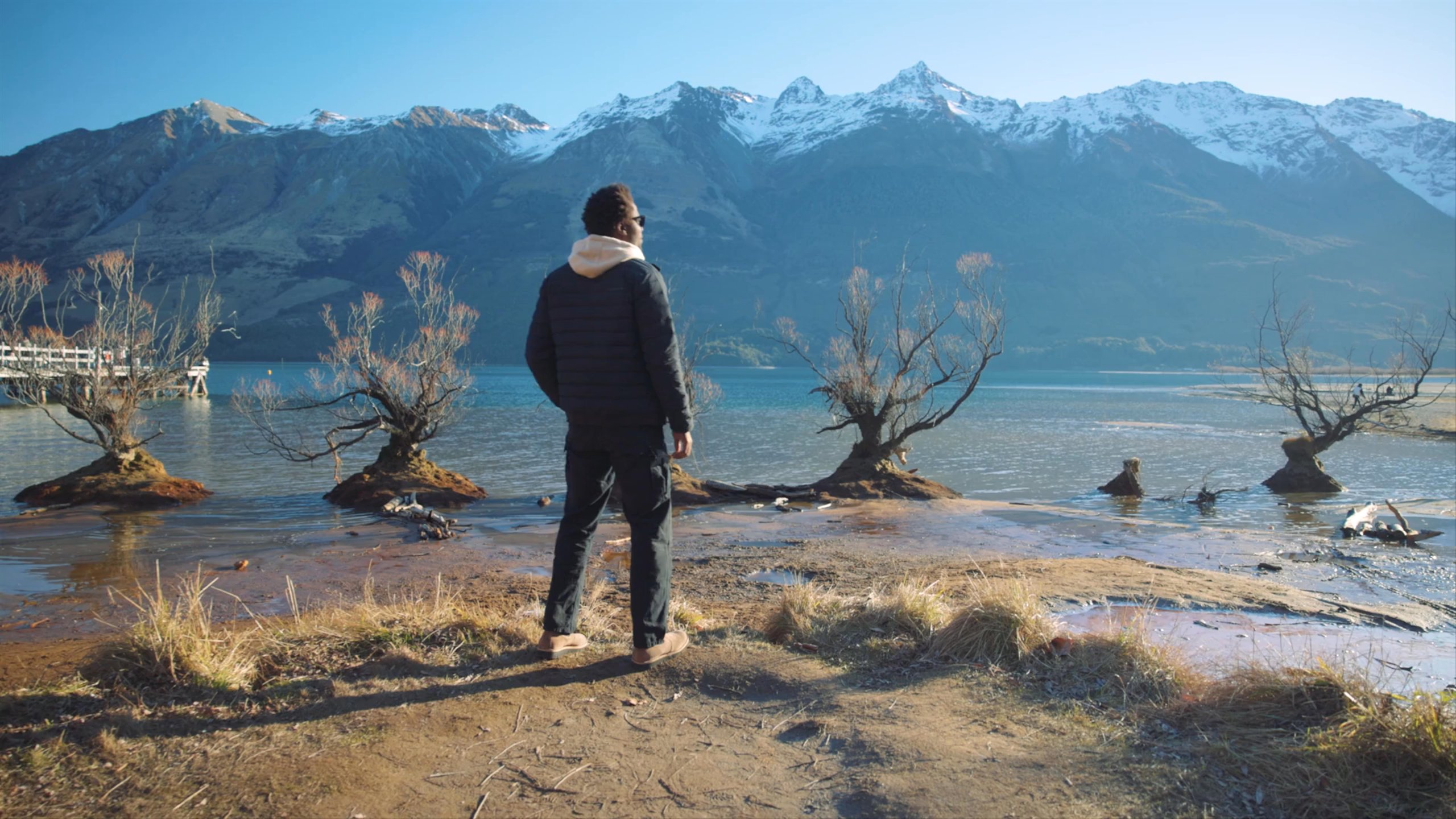 Man standing by a lake in New Zealand, body turned to camera