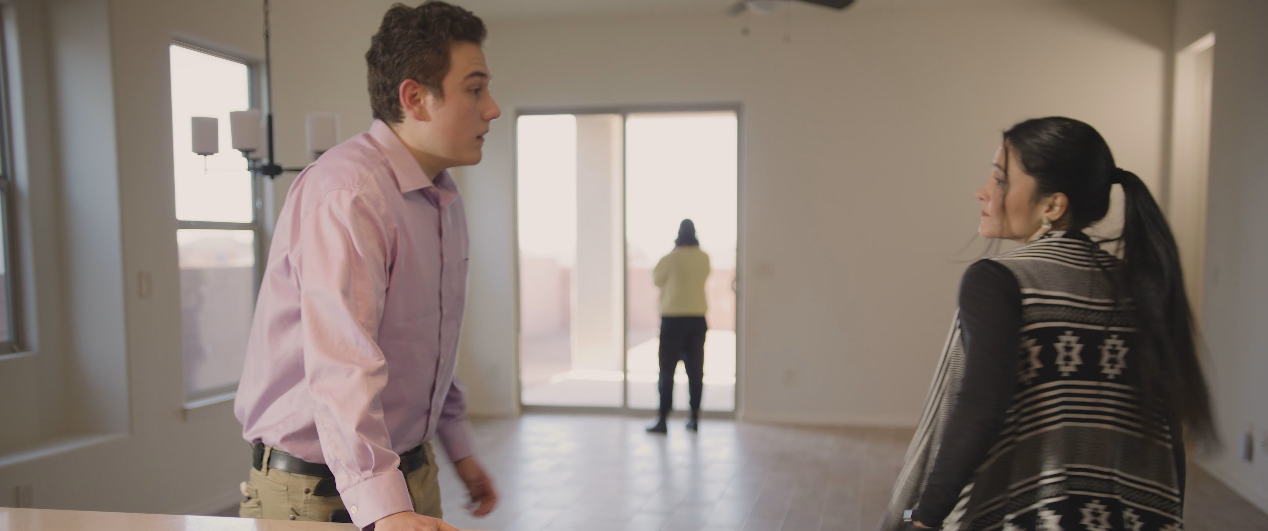 A man and a woman engage in a focused conversation while standing in the spacious, open-concept living area of a house. The pair moves through the interior space, evaluating the property together.