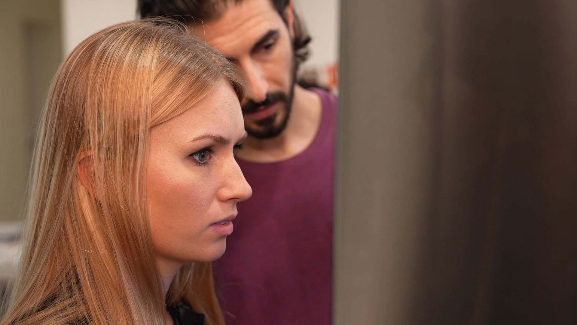 A group of family members engage in a tense conversation within a home setting, characterized by serious facial expressions and uneasy interaction. The scene transitions between different rooms, highlighting the somber emotional atmosphere and dialogue-heavy narrative.