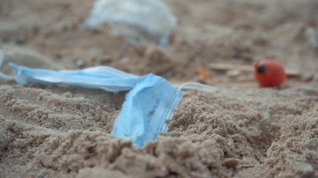 A dirty beach with plastic being blown about by the wind