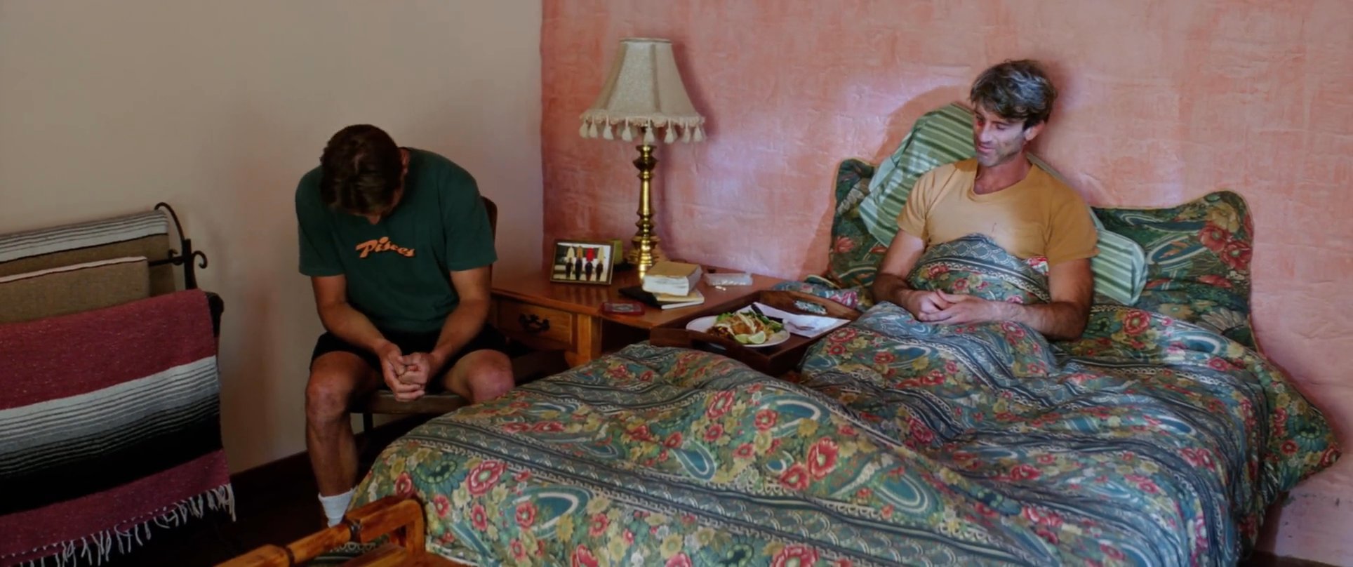 A visitor consults with a patient recovering in a hospital room before departing the premises in a vintage pickup truck.