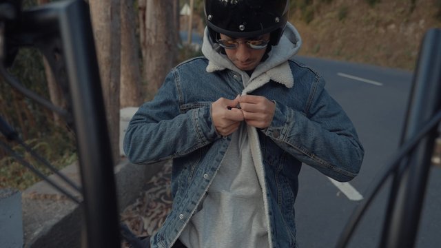 A motorcyclist buttoning his jacket and preparing to leave