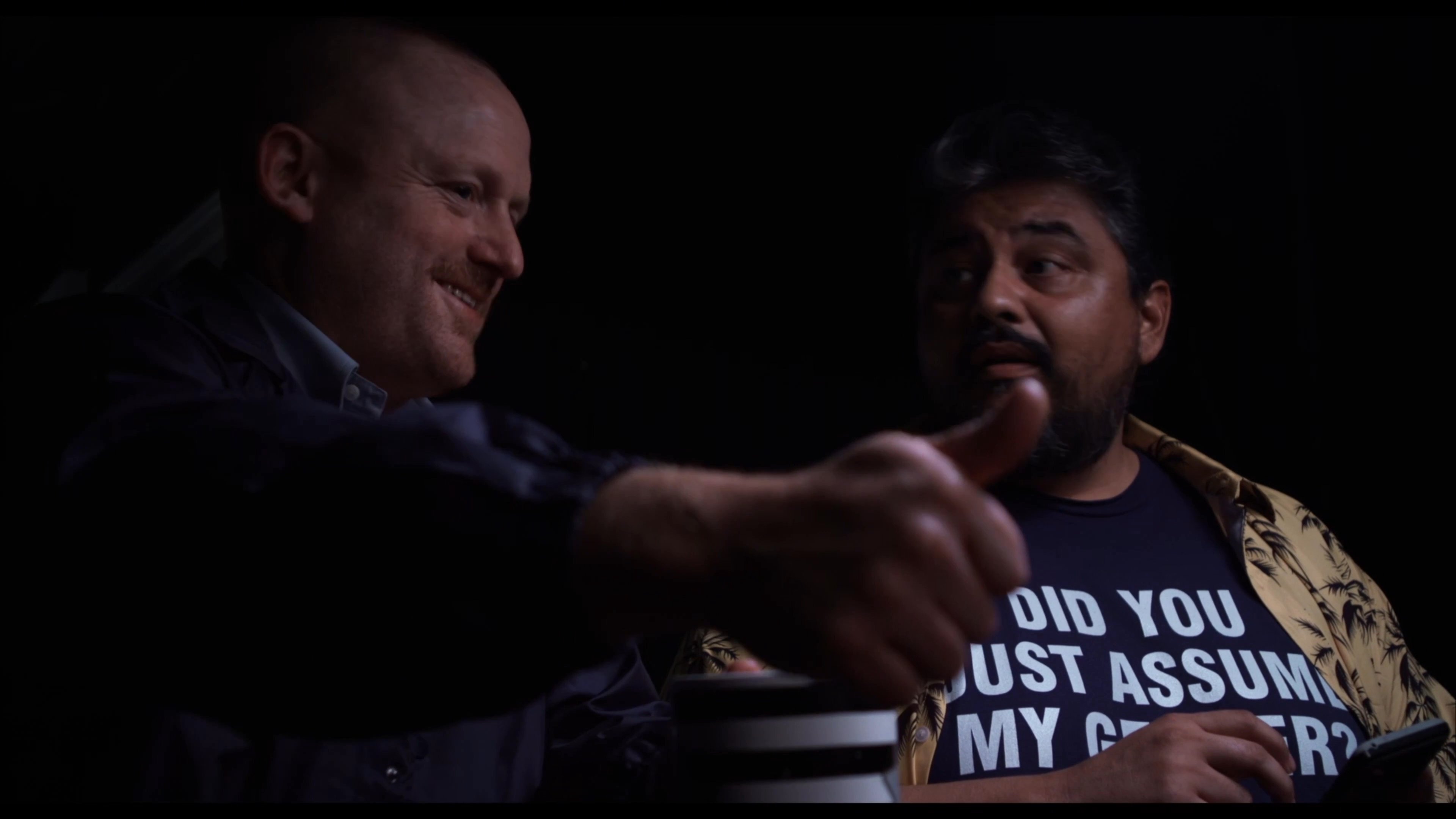 A DEA agent interrogates individuals in a darkened room, transitioning between the questioning session and the prisoners' reactions. The exchange concludes as the agent leads one of the subjects out of the room.