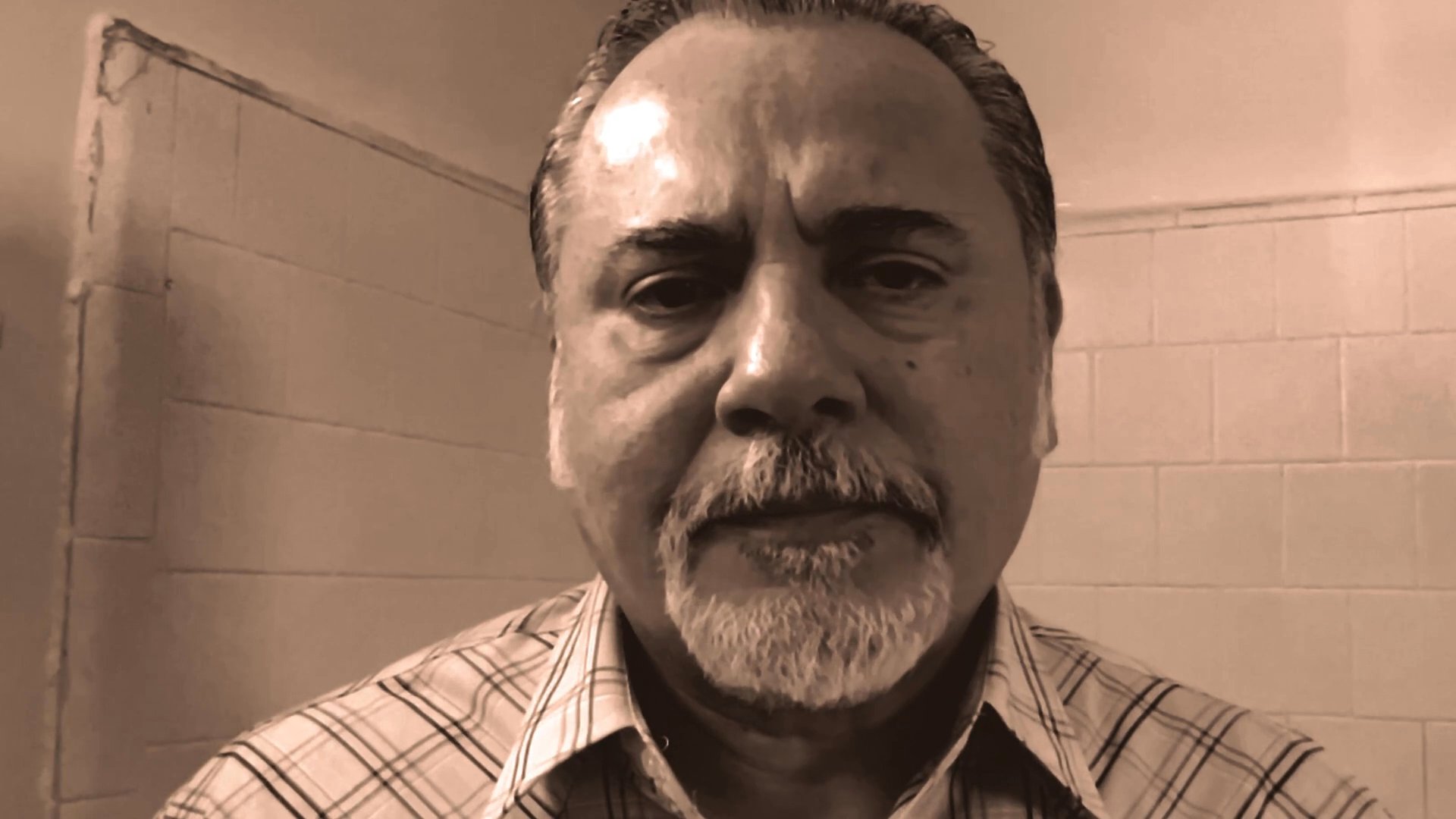 A middle-aged man with a goatee gazes directly at the camera while speaking in a thoughtful, serious tone against a neutral background.