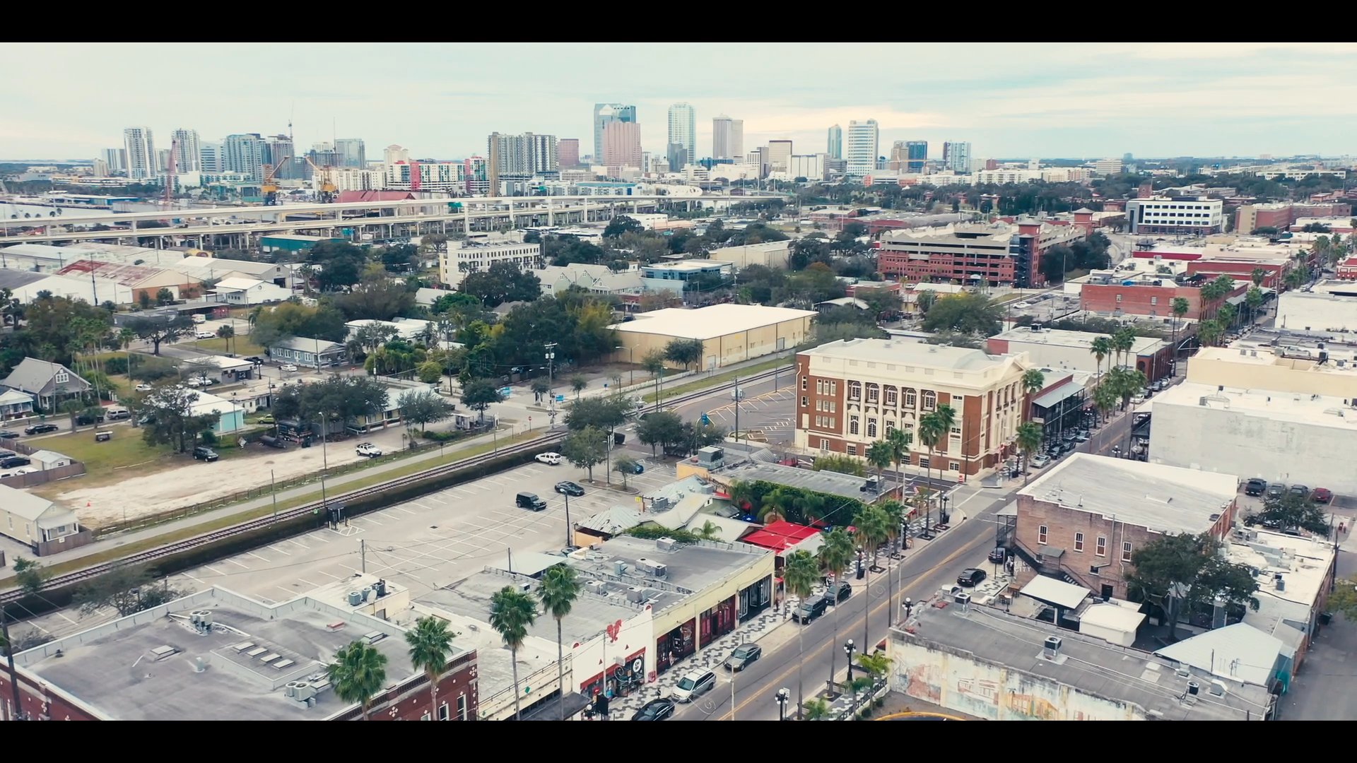 A chef prepares ingredients in a kitchen setting while a professional walks outdoors with a beverage, interspersed with aerial footage of a city landscape.