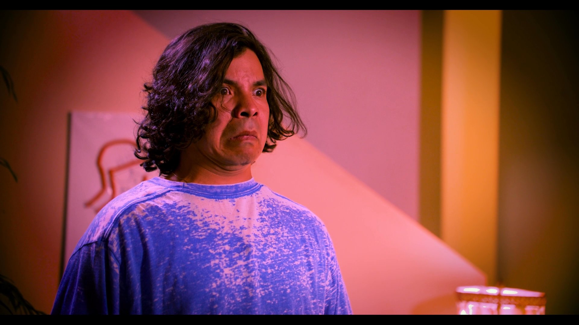 A man and a woman maintain a long-distance connection through a video call, sharing artwork and personal interactions within their respective living spaces.