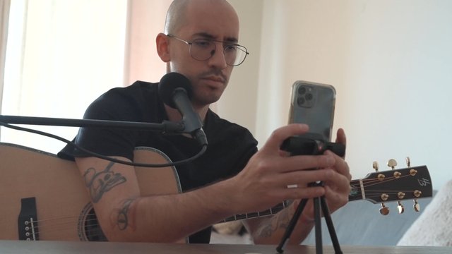 A guy setting up his phone camera to record his music performance