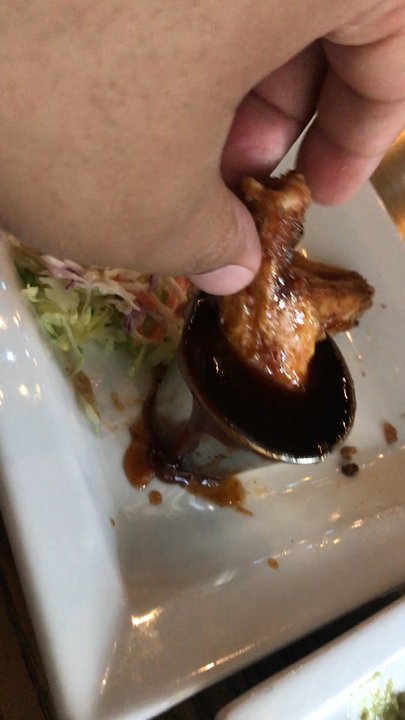 Mezcal Tequila Kitchen - Dipping wing in the sweet habanero sauce. - Mexican Near Me - Worcester, Massachusetts