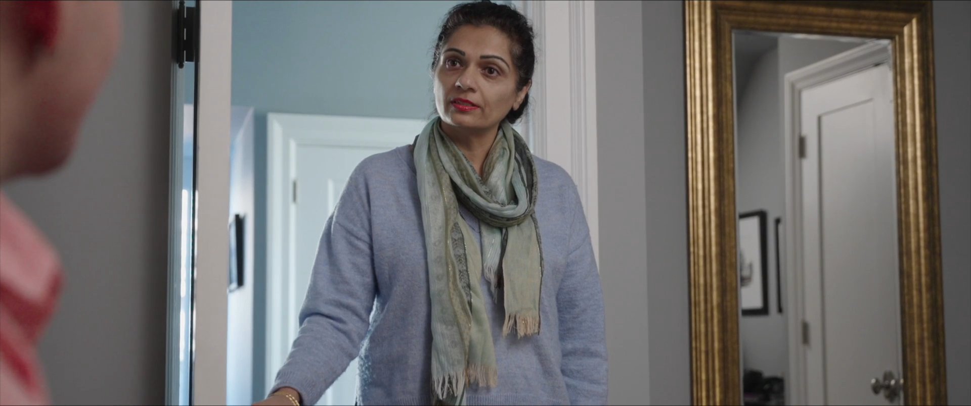 A young man and an older woman engage in a conversational exchange within a residential setting.
