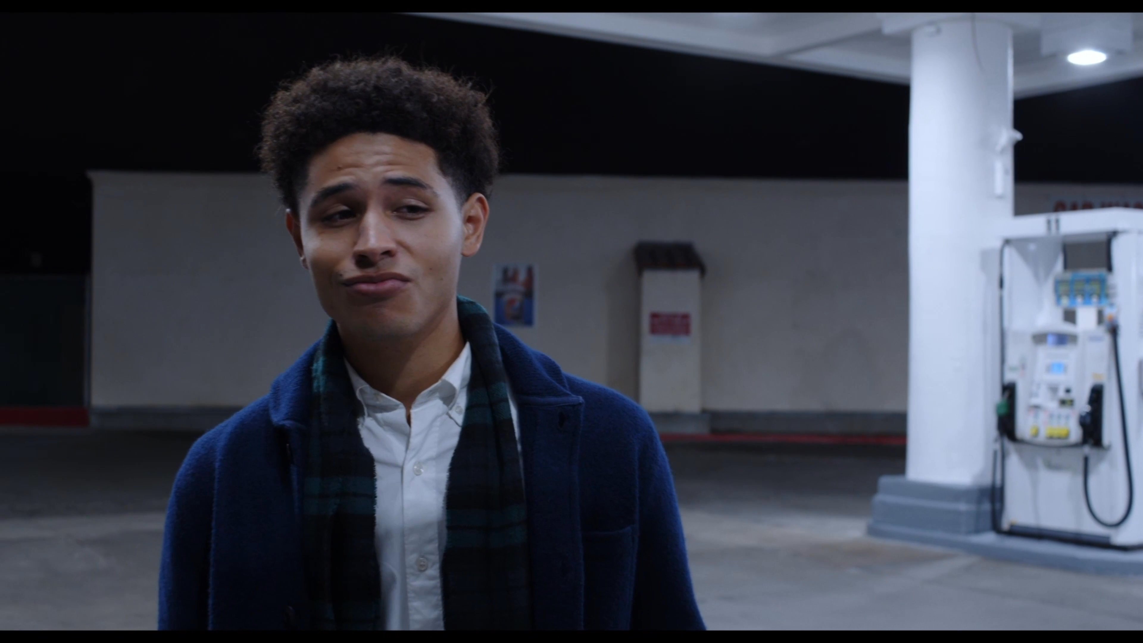 Two men engage in an animated discussion while standing at a deserted gas station late at night.