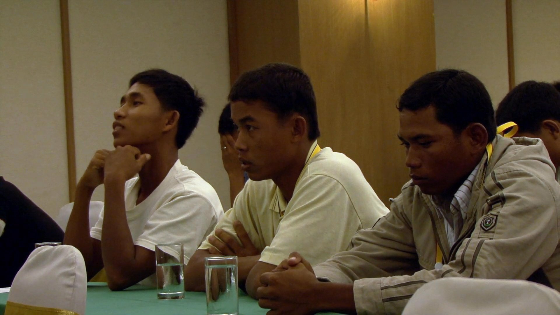 A coach leads a training session for a group of young athletes in a formal conference setting.