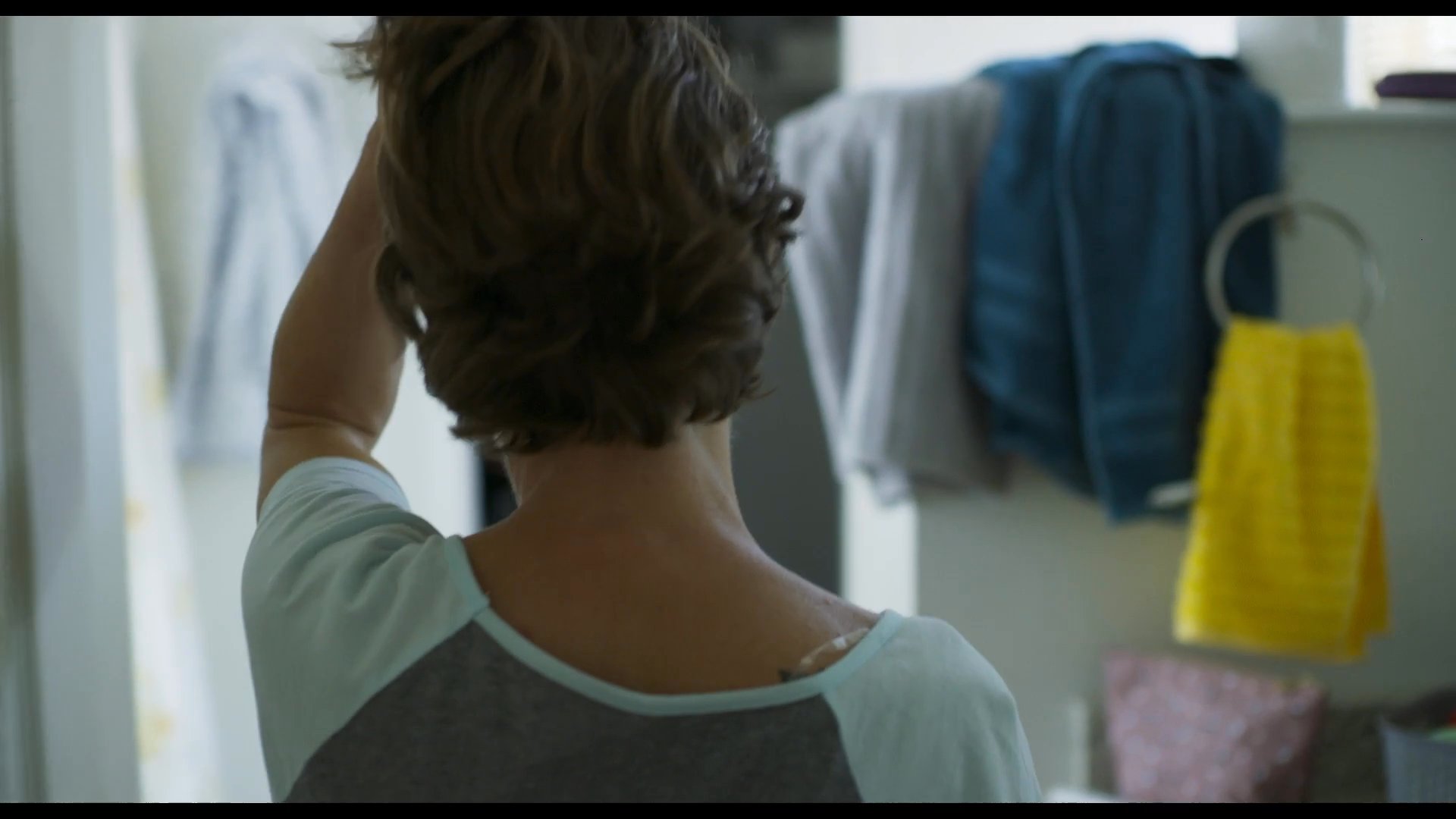 A woman explores a quiet bedroom before looking inside a closet containing packed baby equipment. Her demeanor suggests a moment of personal reflection or preparation within a residential setting.