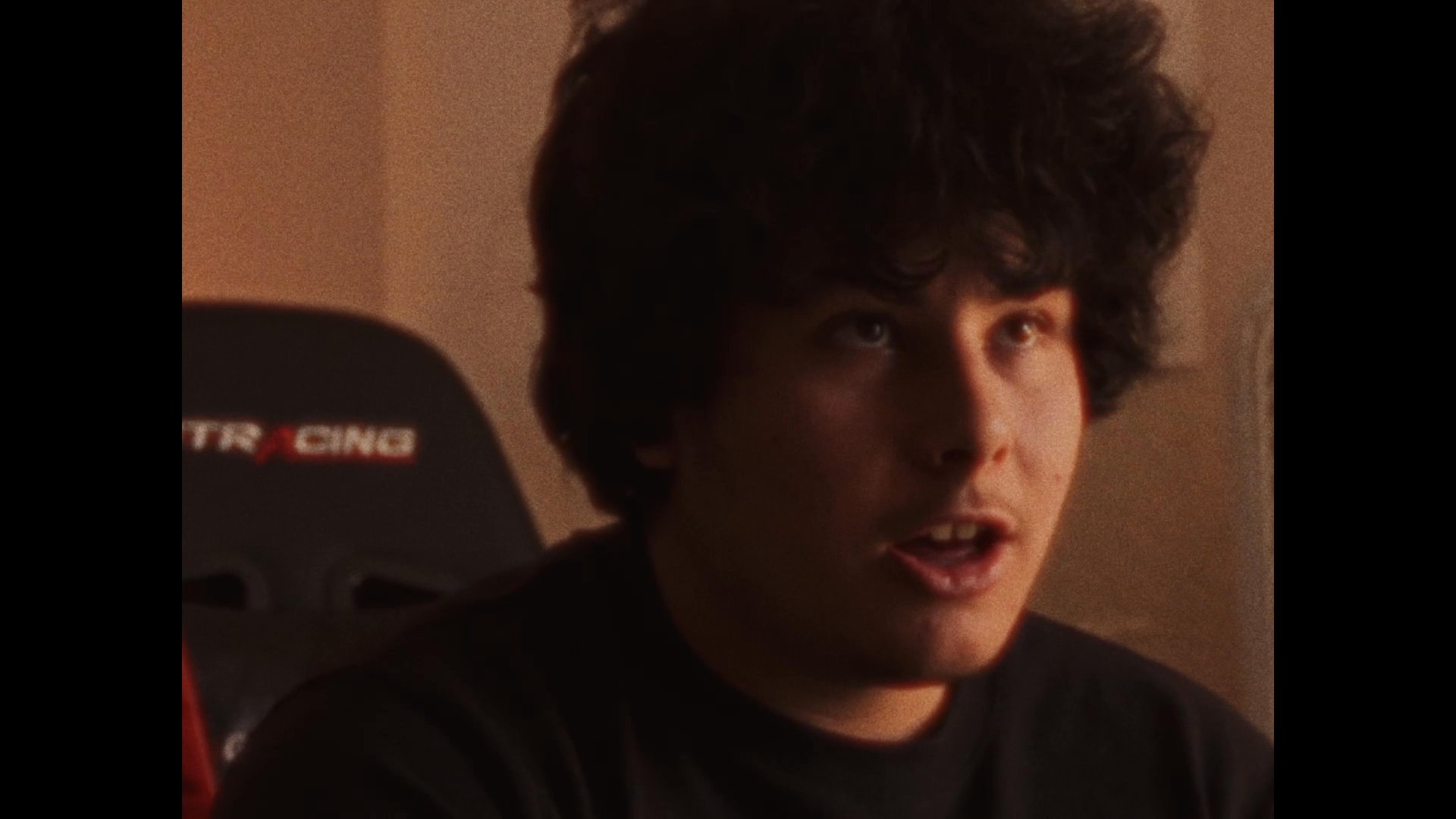 An aerial view of a residential property transitions to an interior shot of a young man engaged in a conversation, followed by a close-up of an elephant-shaped ornament.