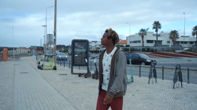 A man walking on a sidewalk toward the beach