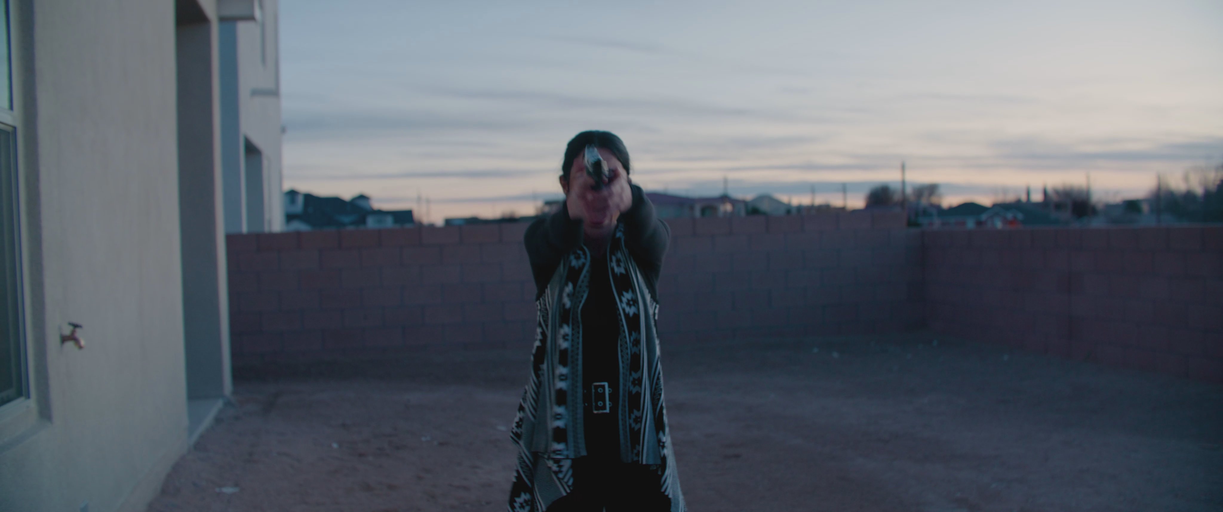 A woman strategically maneuvers through a residential backyard before engaging in an armed confrontation with two individuals. She discharges her weapon, neutralizing an adversary, before the scene concludes with her tense reaction.
