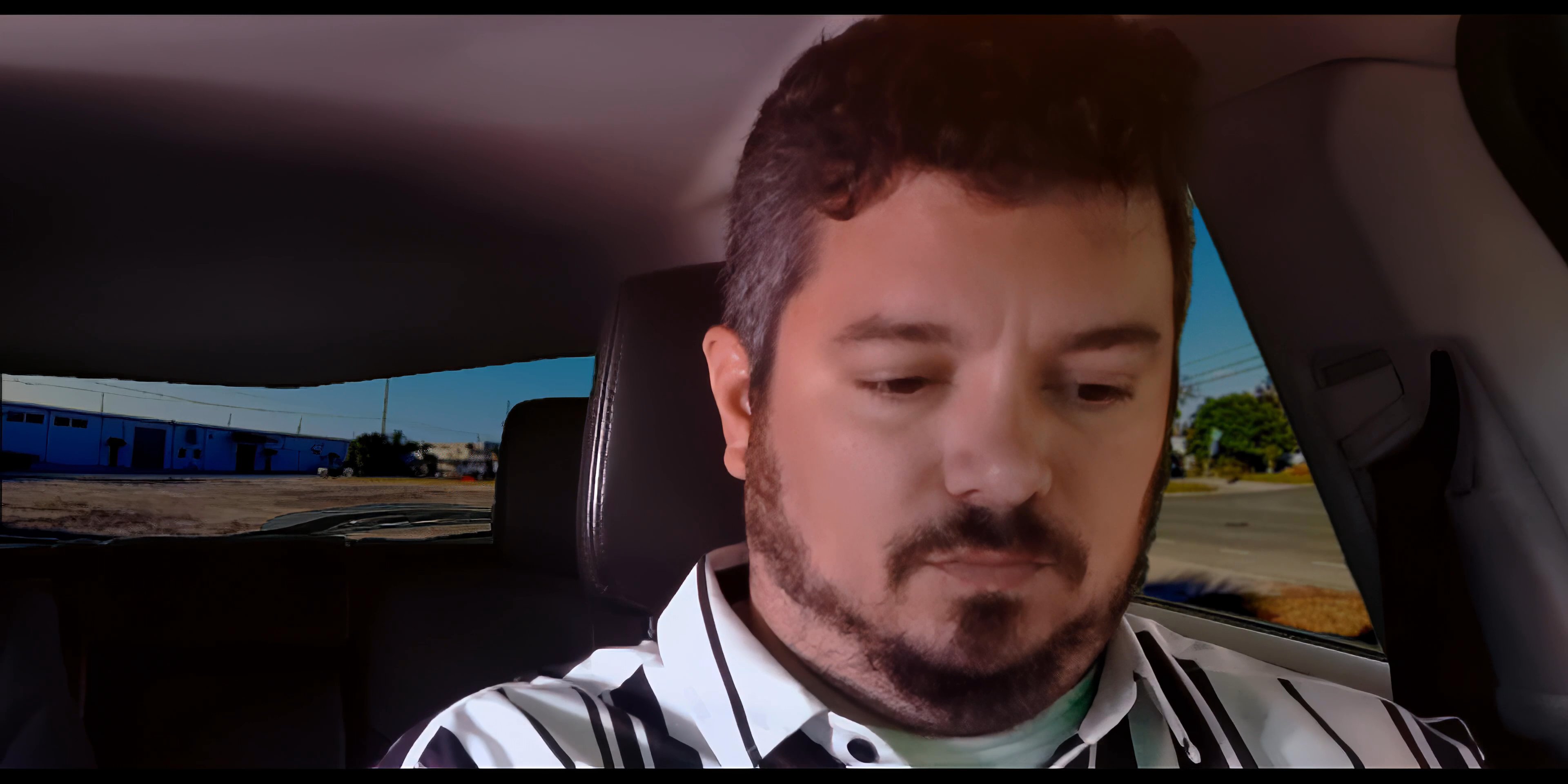 Two men engage in a serious discussion while seated inside a moving vehicle. The passenger focuses intently while the driver provides input during their shared journey.